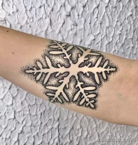 Фото тату: снежинка, выполненная точками (dotwork) на руке. Крупный и детализированный рисунок татуировки с использованием техники точечной штриховки.