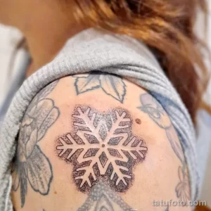 Фото тату: снежинка, выполненная точками (dotwork) на лопатке. Минималистичный и стильный рисунок татуировки с использованием техники точечной штриховки.