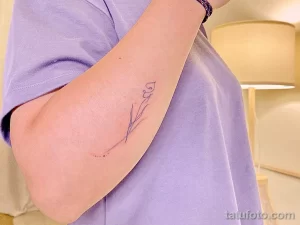 Фото тату: Тонкая татуировка ветки с маленьким сердцем на конце, выполненная тонкими линиями на предплечье. Минималистичный дизайн.