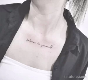 Фото тату: черная надпись "Believe in yourself" на груди девушки. Элегантная и мотивирующая татуировка, расположенная под ключицами.