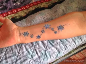 Фото тату: ряд маленьких голубых снежинок на внутренней стороне запястья, выполненных в минималистичном стиле.