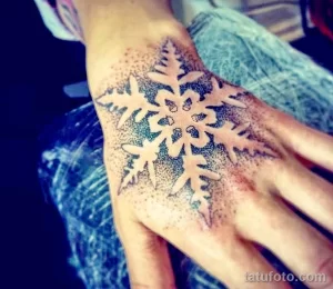 Фото тату: снежинка, выполненная в технике dotwork на руке. Черно-белая татуировка с акцентом на детализацию и графичность.