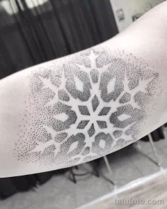 Фото тату: большая снежинка, выполненная в технике dotwork на предплечье. Черно-белая татуировка с акцентом на детализацию и графичность.