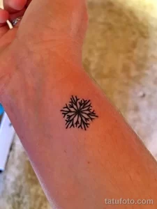 Фото тату: маленькая, черная снежинка, выполненная в минималистичном стиле, расположена на запястье. Идеальный вариант для тех, кто ценит лаконичность.
