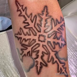 Фото тату: большая снежинка на руке, выполненная в технике blackwork. Детализированный рисунок татуировки с использованием черного цвета и различных оттенков серого.