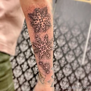 Фото тату: масштабная татуировка снежинок, выполненная в технике dotwork, покрывает часть руки. Детализированный и впечатляющий рисунок.
