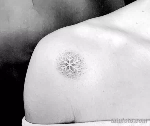 Фото тату: минималистичная снежинка, выполненная точечной техникой (dotwork), расположена на плече. Элегантный и современный рисунок.