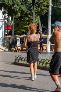 Фото тату на спине женщины с большим, красочным цветочным рисунком. Преобладают красные, розовые и зеленые оттенки, создающие эффект живых цветов.