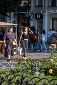 Фото девушки с татуировками на руках, идущей по улице. Черно-белые тату, современный стиль, уличная мода, повседневный образ.