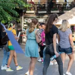 Фотография девушки, идущей по улице с татуировкой льва на плече. Татуировка выполнена в черно-белой гамме и имеет реалистичный вид.