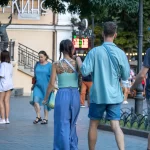Фотография девушки с татуировкой на спине, идущей по улице. Видна детализированная татуировка в стиле ботаники.