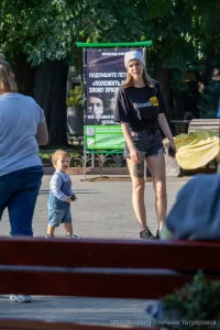 Фотография девушки, идущей по улице с видимой татуировкой на ноге. На заднем плане городской пейзаж и рекламный баннер.
