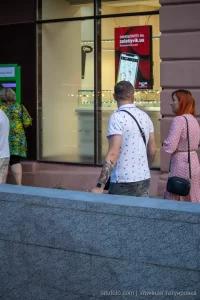 Фото тату на руке мужчины, стоящего на улице. Видны детализированные рисунки на плече и предплечье, выполненные в темных тонах.