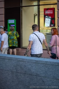 Фото тату на руках мужчины, одетого в белую рубашку с принтом. Видны детализированные рисунки на плече и предплечье.