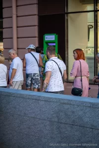 Фото тату на руке мужчины, идущего по улице. Видны детализированные рисунки на плече и предплечье, выполненные в темных тонах.