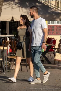 Фото тату на предплечье мужчины: реалистичная змея обвивается вокруг черепа, выполненная в черных тонах с детальной проработкой чешуи и костей.