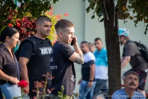 Фото тату на руке мужчины, вид сбоку, он разговаривает по телефону на улице, летний день, городская среда.