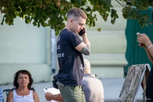 Фото тату на руке мужчины, вид сбоку, он разговаривает по телефону на улице, летний день, городская среда.