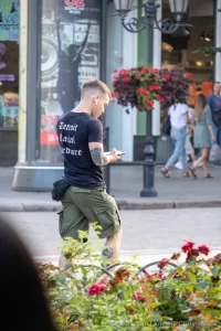 Фото тату на руке мужчины, вид сбоку, он разговаривает по телефону на улице, летний день, городская среда.
