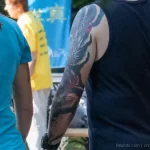 Фото тату: большая татуировка японского дракона на руке мужчины, выполненная в традиционном японском стиле, яркие цвета, детализированный рисунок.
