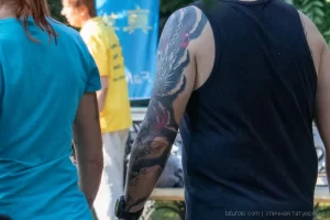 Фото тату: большая татуировка японского дракона на руке мужчины, выполненная в традиционном японском стиле, яркие цвета, детализированный рисунок.