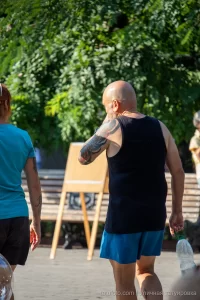 Фото тату: большая татуировка на плече мужчины, с изображением ярких цветов и абстрактных элементов, выполненная в смешанном стиле.