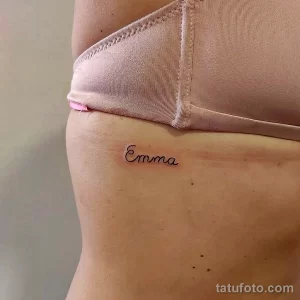 Фото тату на боку: надпись 'Emma', выполненная простым шрифтом, расположена на коже.