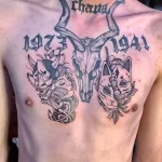 Мужская татуировка на груди с изображением черепа, масок кицунэ и они, а также надписей с датами. Тату выполнено в традиционном японском стиле.