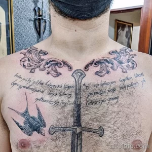 Фото тату на груди мужчины с изображением меча, ласточки и эльфийской вязи. Татуировка выполнена в черном цвете.