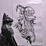 Фото тату Анубиса с косой в стиле old school. Яркий рисунок с четкими контурами и насыщенными цветами, изображающий древнеегипетского бога с атрибутами жнеца.