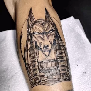 Фото тату Анубиса в стиле blackwork на руке. Детализированное изображение головы бога с шакалом и традиционными египетскими элементами.