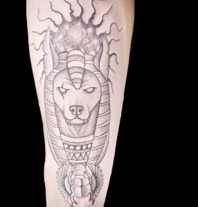 Фото татуировки Анубиса в стиле dotwork, выполненной с использованием точек и штрихов на предплечье.