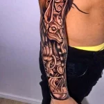 Фото татуировки Анубиса в стиле blackwork, с использованием плотных черных заливок и геометрических узоров на предплечье.