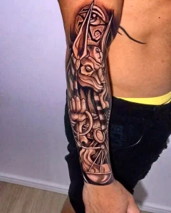 Фото татуировки Анубиса в стиле blackwork, с использованием плотных черных заливок и геометрических узоров на предплечье.