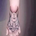 Черно-серая татуировка Анубиса на руке, детально проработанная, с акцентом на голове и воротнике. Идеальный эскиз тату для поклонников египетской мифологии.