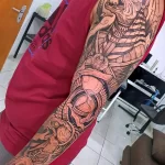 Фото масштабной татуировки Анубиса на всю руку. Изображение выполнено в черно-белой гамме с детализированной прорисовкой египетских символов и узоров.
