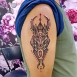 Фото татуировки Анубиса на плече, выполненной в геометрическом стиле. Изображение состоит из четких линий и фигур, создающих абстрактный портрет бога.