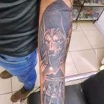 Фото татуировки Анубиса на предплечье в стиле blackwork. Чёрные тона, детализированная морда, взгляд, направленный в сторону.