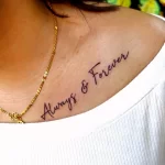 Черно-белое фото татуировки на груди с надписью "Always & Forever", выполненной красивым рукописным шрифтом. Татуировка символизирует вечную любовь.