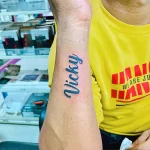 Фото тату: надпись "Vicky" каллиграфическим шрифтом на внутренней стороне предплечья.