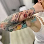 Фото тату: реалистичный портрет девушки с ярким макияжем на предплечье, выполненный в красочной технике.