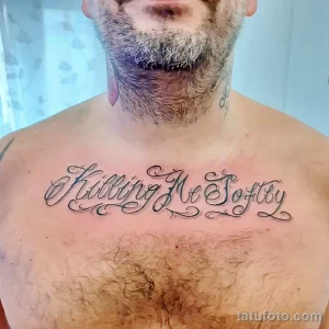 Фото тату: на груди мужчины выполнена татуировка надписью 'Killing Me Softly' в изящном шрифте, выполненная в черных чернилах.
