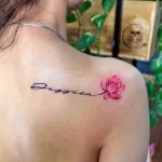 Фото тату: женское плечо украшено изящной надписью 'Jessica' и нежной розой, выполненной в акварельной технике.