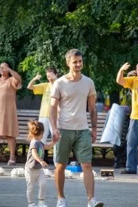 Фото тату на руке мужчины, держащего за руку маленькую девочку. Татуировка изображает темные деревья на фоне светлой кожи.