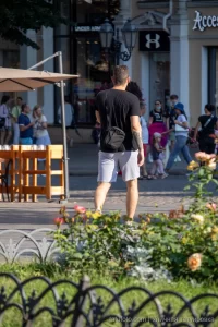 Фото тату на руке мужчины, идущего по городской улице. Видна часть татуировки в черном цвете.