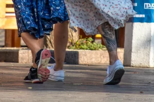 Фото татуировки на ноге, изображающей череп, обвитый цветами. Татуировка выполнена в реалистичном стиле с использованием черных и серых оттенков.