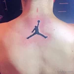 Фото тату на шее с изображением логотипа Jumpman (силуэт Майкла Джордана в прыжке). Черная татуировка в минималистичном стиле.