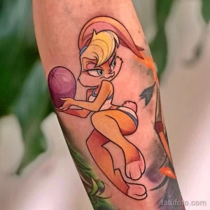 Мультяшная татуировка на руке, изображающая Лолу Банни из Looney Tunes, бегущую с баскетбольным мячом, в ярких и насыщенных цветах.