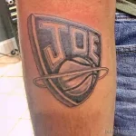 Фото тату на предплечье с изображением баскетбольного щита и надписью 'JOE'. Черно-белая гамма, минималистичный стиль.