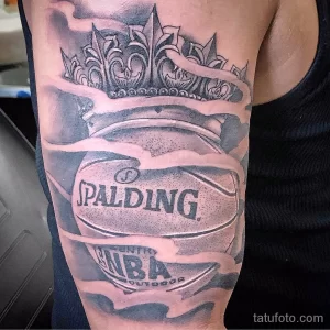 Фото тату на предплечье: баскетбольный мяч Spalding под короной, выполненный в черно-серых тонах с реалистичной детализацией.